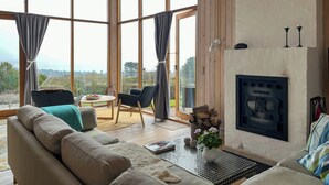 Amplia sala de estar con chimenea, ventanas grandes y vistas al exterior.