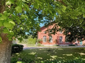 Un bâtiment en briques rouges, avec une pelouse et des arbres au premier plan.