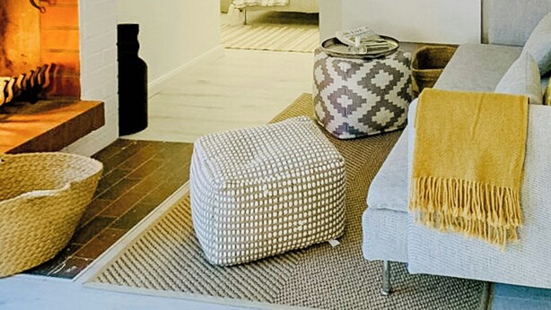 A cozy living room with a fireplace, a sofa, ottomans, and a patterned throw. - Thatched holiday home by the Baltic Sea (Großenbrode)