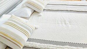 A room with a sloped ceiling, a view of a wooden deck, and a bed with white bedding and patterned pillows. - Thatched holiday home by the Baltic Sea (Großenbrode)