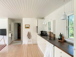 Eine Küche mit Holzboden, weißen Schränken, einer dunklen Arbeitsplatte, einer Pendelleuchte und einem Fenster mit Blick.
