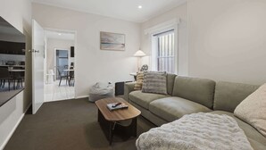 A living room with a sofa, a coffee table, a lamp, and a painting on the wall. - Hobart CBD Loft - Walking to CBD (Hobart)