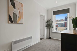 Ein Zimmer mit Heizkörper, Tür, Fenster mit Blick und einer Topfpflanze.