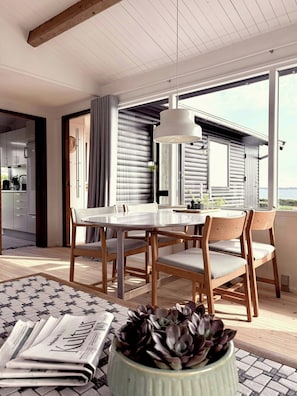 A dining area with a round table, wooden chairs, and a potted plant. - Beach villa overlooking South Funen Archipelago (Faaborg)