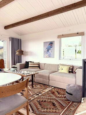 A modern living room with a sectional sofa, a round dining table, and a patterned rug. - Beach villa overlooking South Funen Archipelago (Faaborg)