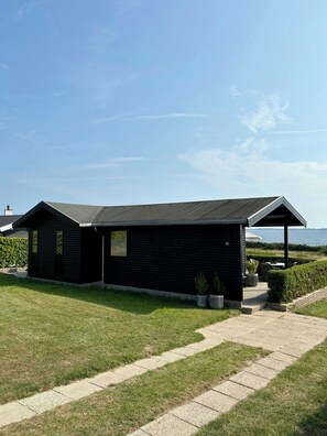 A modern building with a flat roof, a covered patio area, and a pathway leading to the entrance. - Beach villa overlooking South Funen Archipelago (Faaborg)