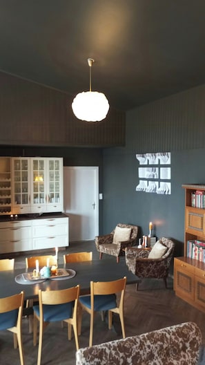 A dining area with a table, chairs, a chandelier, a cabinet with glass doors, and a bookshelf. - Renovated chapel with fjord views in Vågstranda (Vågstranda)
