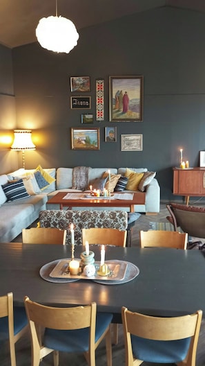 A dining area with a table set for four, a sofa, and a wall with framed artwork. - Renovated chapel with fjord views in Vågstranda (Vågstranda)