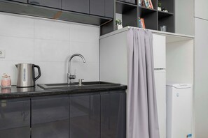 A modern kitchen with a stainless steel kettle, a sink, and a white refrigerator. - Cozy Apartment | Near the Banksy Museum (Kraków)