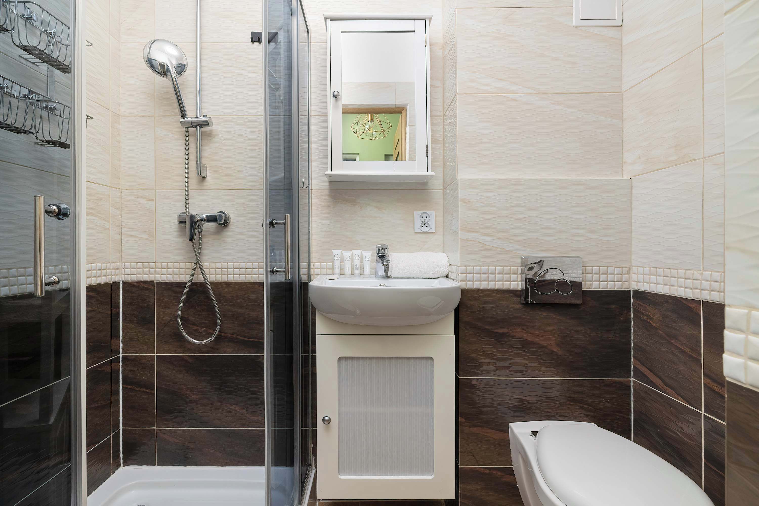 A bathroom with a glass shower enclosure, a white sink, and a toilet.