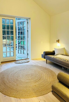 Ein Zimmer mit einer Couch, einem Teppich und einer Tür, die nach draußen führt.