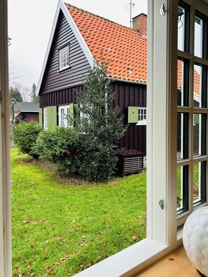 Ein Haus mit geneigtem Dach, einem markanten Schornstein und einem gepflegten Rasen.