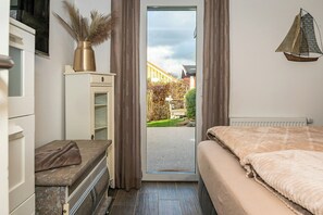Ein Schlafzimmer mit Bett, Kommode, Schminktisch und Blick ins Freie.