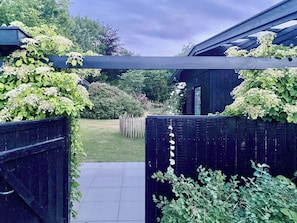 Ein Gartenweg führt zu einem Gebäude mit Holzzaun und viel Grün.