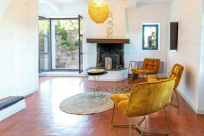 A spacious living room with a fireplace, a large window, and a view of the outdoors. - 17th century Provençal farmhouse with pool (Le Plan de la Tour)