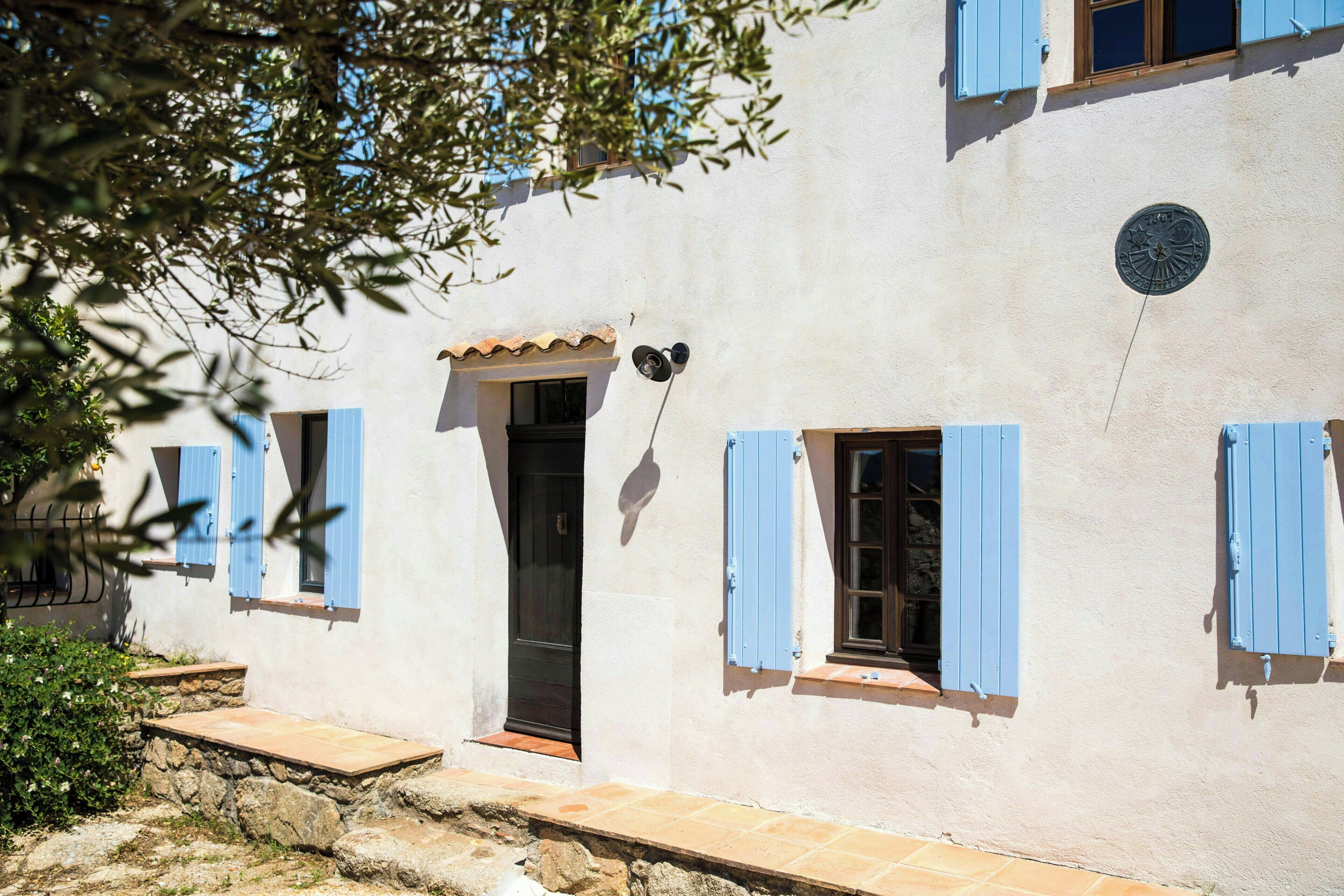 Un edificio con una scala in pietra, una porta e persiane blu.