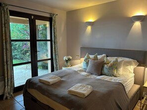 Ein Schlafzimmer mit einem großen Bett, zwei Wandleuchten, einem Nachttisch und einem Fenster mit Vorhängen.
