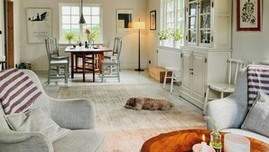 Un salon chaleureux avec un chien, un coin repas et un meuble blanc aux portes vitrées.