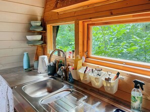 Eine Küche mit Spüle, Holzböden und einem Fenster mit Blick auf Grünfläche.