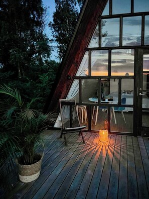 Eine Holzterrasse mit Stuhl, Tisch und einer Topfpflanze.