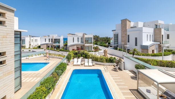 A modern hotel with two swimming pools, outdoor seating, and a clear blue sky. - Lombardi Villa Protaras (Protaras)