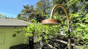 Ein Garten mit einem Springbrunnen aus Metall, umgeben von viel Grün und einem Haus.