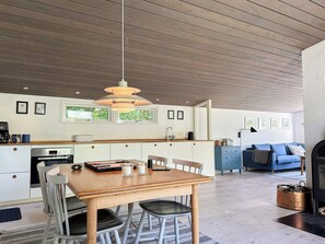 Eine moderne Küche mit Holzboden, einem Esstisch mit Stühlen, einer Kaffeemaschine und einem Herd.