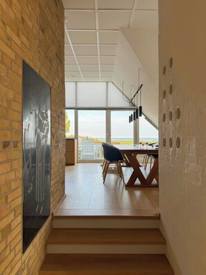 Een modern interieur met een bakstenen muur, een eethoek met een tafel en stoelen, en uitzicht op de omgeving.