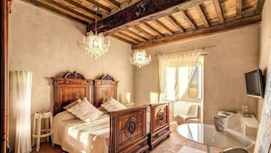 Een slaapkamer met een houten bed, een kroonluchter, een televisie en een klein rond tafeltje.