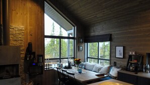 Una cocina moderna con chimenea de piedra, ventanas amplias y techo de madera.