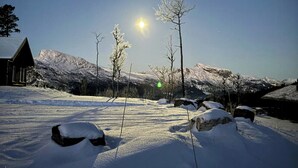 Un paisaje nevado con una montaña al fondo y un edificio con tejado cubierto de nieve.