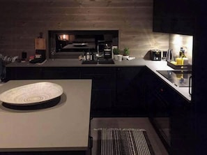 Eine moderne Küche mit Einbauofen, Kaffeemaschine und Spüle.