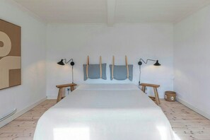 Ein Schlafzimmer mit einem großen Bett, zwei Nachttischen, einer Wandlampe und Holzboden.