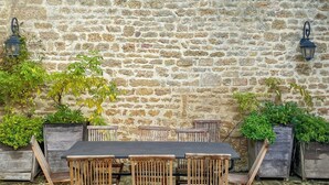 Un mur de pierres avec une table et des chaises devant.