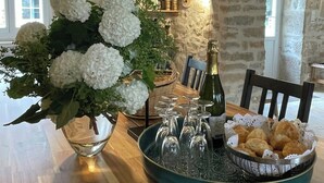 Une table à manger ornée d’un vase de fleurs blanches, d’une bouteille de champagne et d’un plateau de pâtisseries.