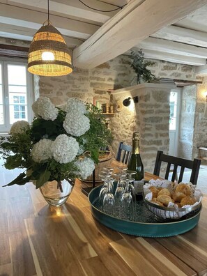 Ein Esstisch mit einer Vase weißer Blumen, einer Champagnerflasche und einer Auswahl an Gebäck.