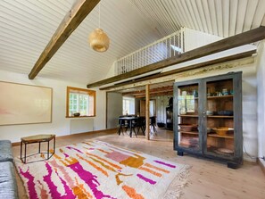 A spacious room with a high ceiling, a dining area, and a kitchen with a rustic cabinet. - Framed structure with annexes in Österlen (Brösarp)