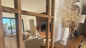 A modern living room with a wooden partition, a sofa, a TV, and a decorative vase with dried flowers. - House with pool in the Cèze valley (Saint Gervais)