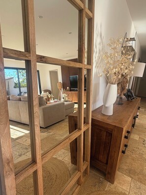 A modern living room with a wooden partition, a sofa, a TV, and a decorative vase with dried flowers. - House with pool in the Cèze valley (Saint Gervais)