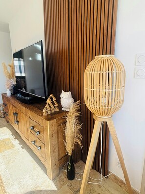 A wooden entertainment center with a flat-screen TV, decorative items, and a tall, woven floor lamp. - House with pool in the Cèze valley (Saint Gervais)