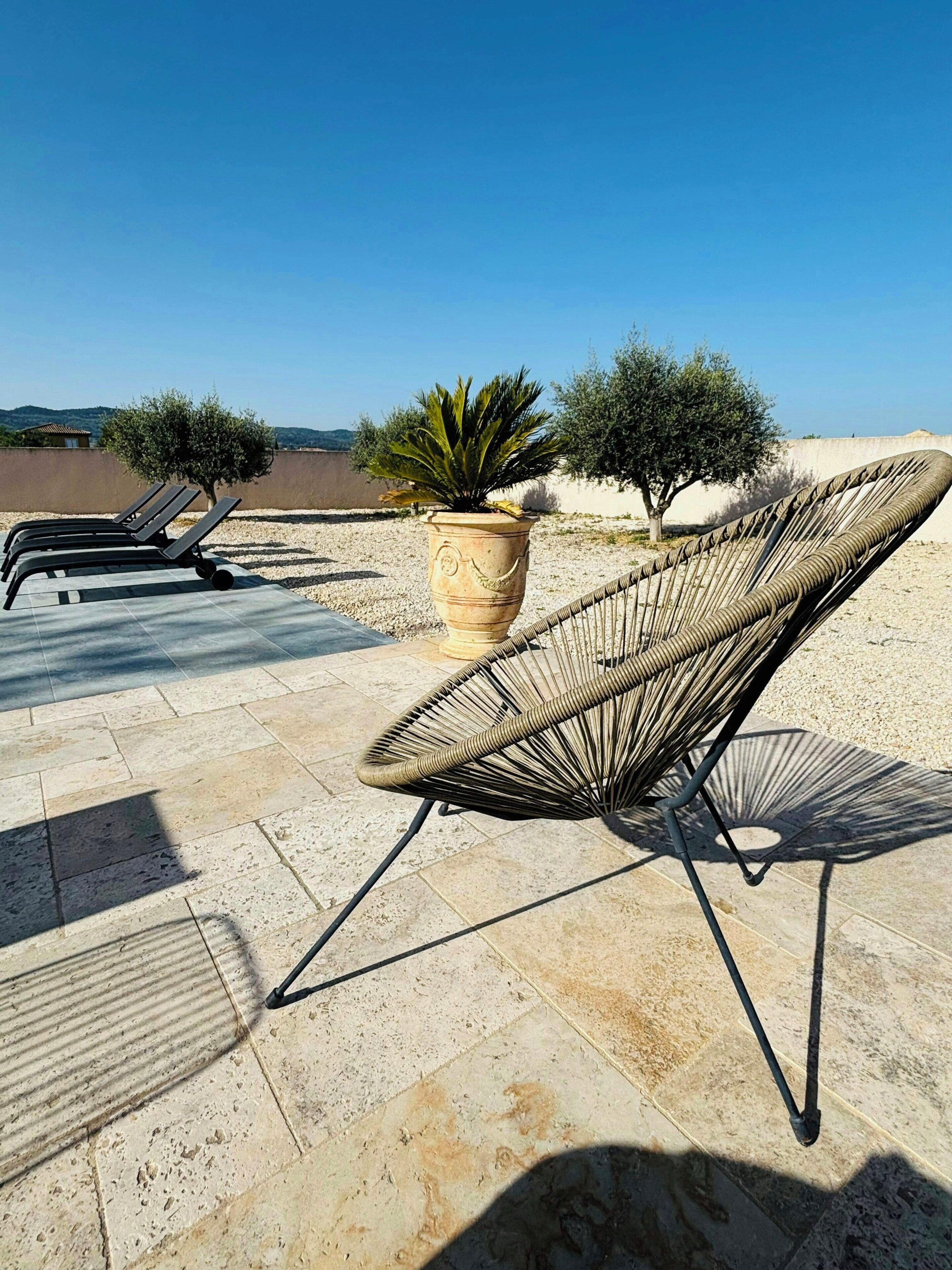 Un espace détente avec des fauteuils, un fauteuil en osier et une plante en pot.