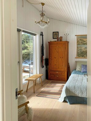 Ein Schlafzimmer mit einem Holzschrank, einem Bett mit blauer Bettdecke, einem Streifen Teppich und einer Kristallleuchter.