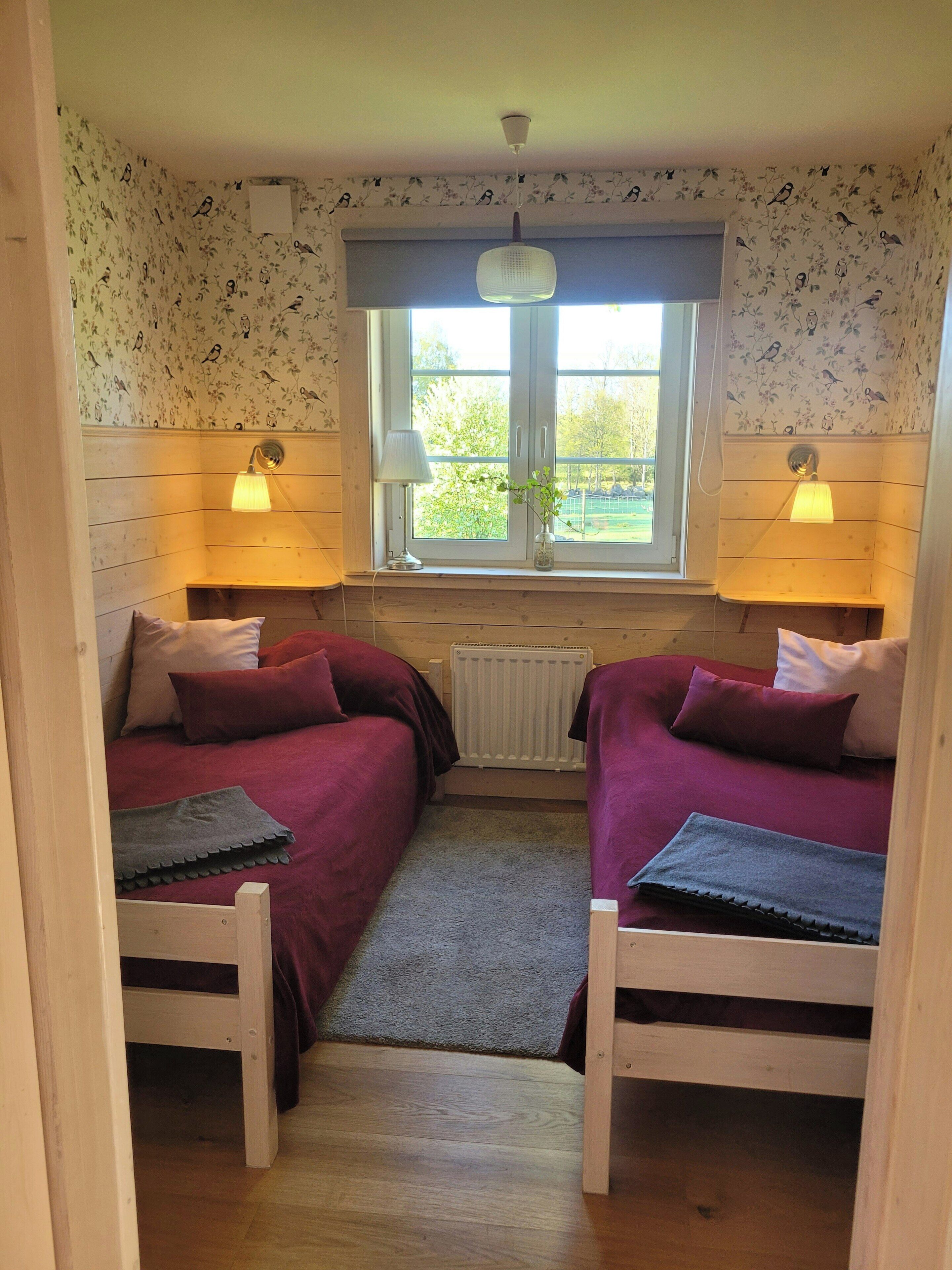 A room with two beds, a window, and a radiator.