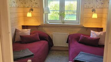 A room with two beds, a window, and a radiator.
