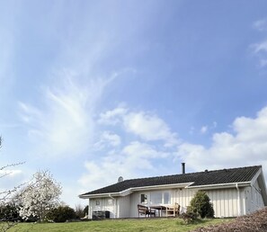 Una casa a un piano con veranda, un camino e cielo sereno.