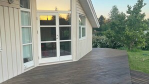 A house with a wooden deck, a sliding glass door, and a small garden area. - Family retreat by Roskilde Fjord (Ølsted)