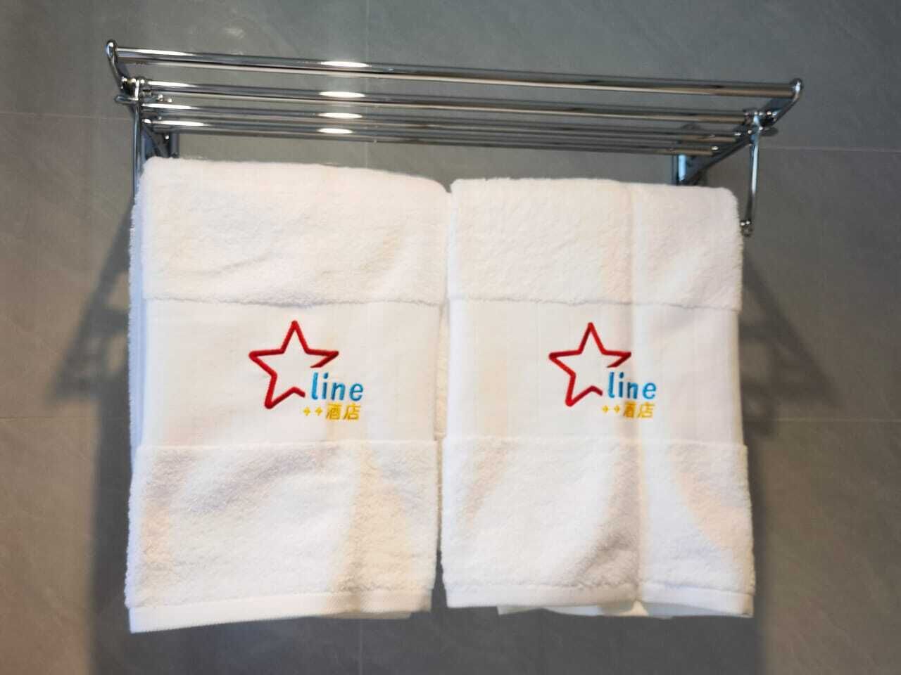 Two white towels hanging on a chrome towel rack in a bathroom.