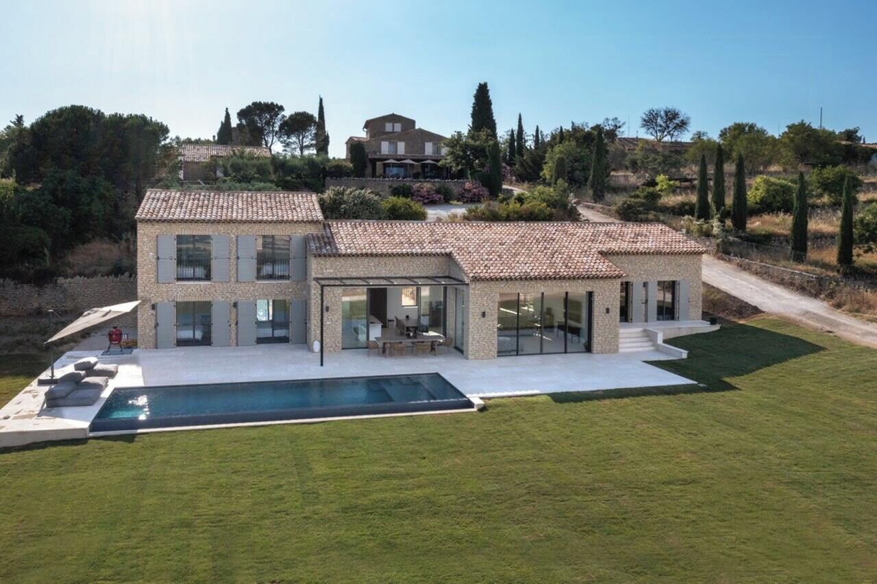 A modern house with a swimming pool, large windows, and a well-maintained lawn.