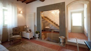 Une pièce comprenant une chaise, une petite table, un radiateur, un escalier et une porte.