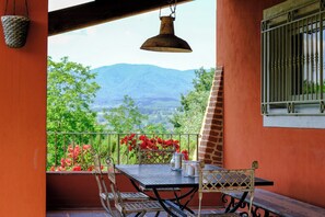 Ein Balkon mit Tisch, Stühlen, einer Hängelampe und Blick auf die Berge.